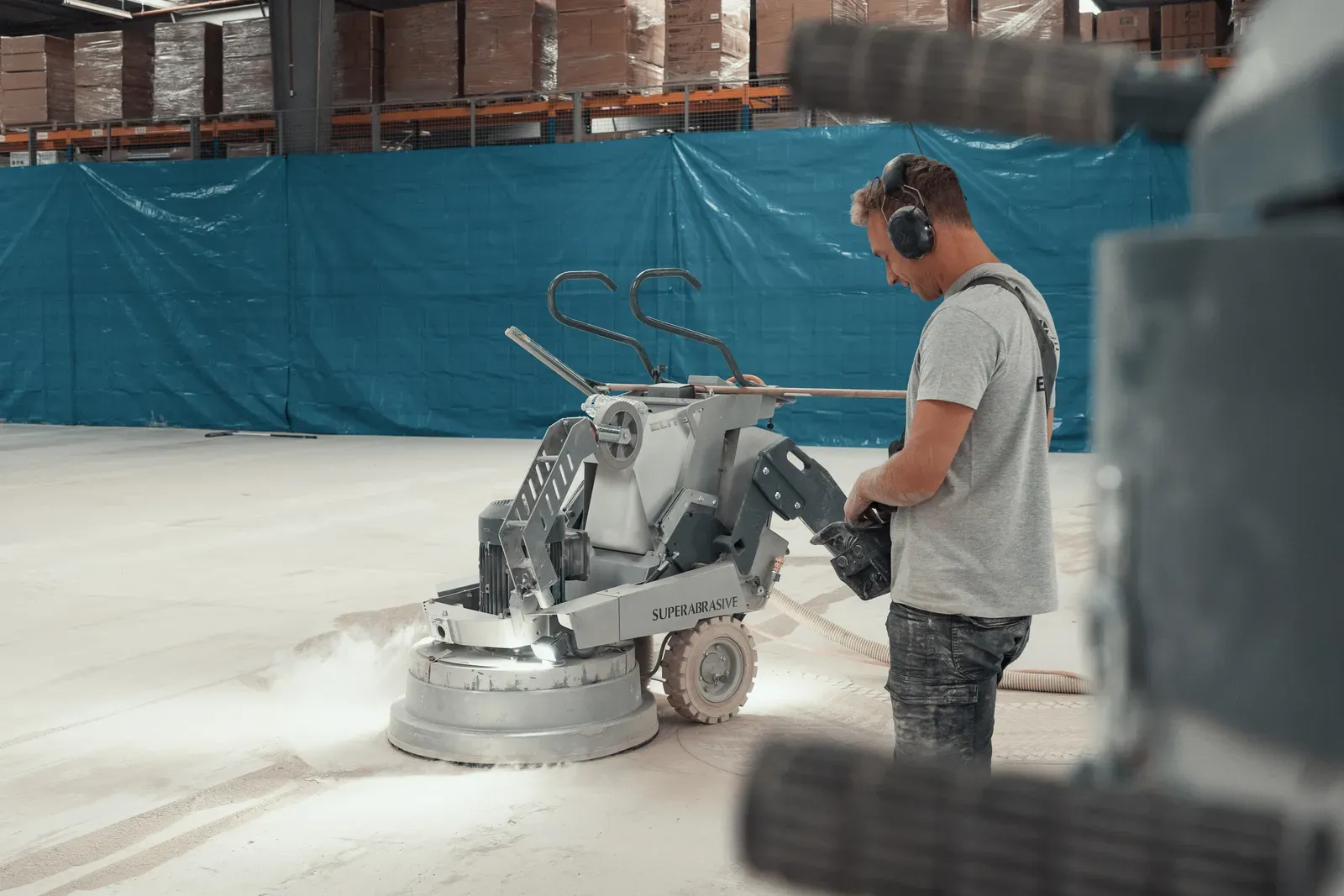 Vakman van Beton Design ruwt een magazijnvloer op met een diamantschuurmachine