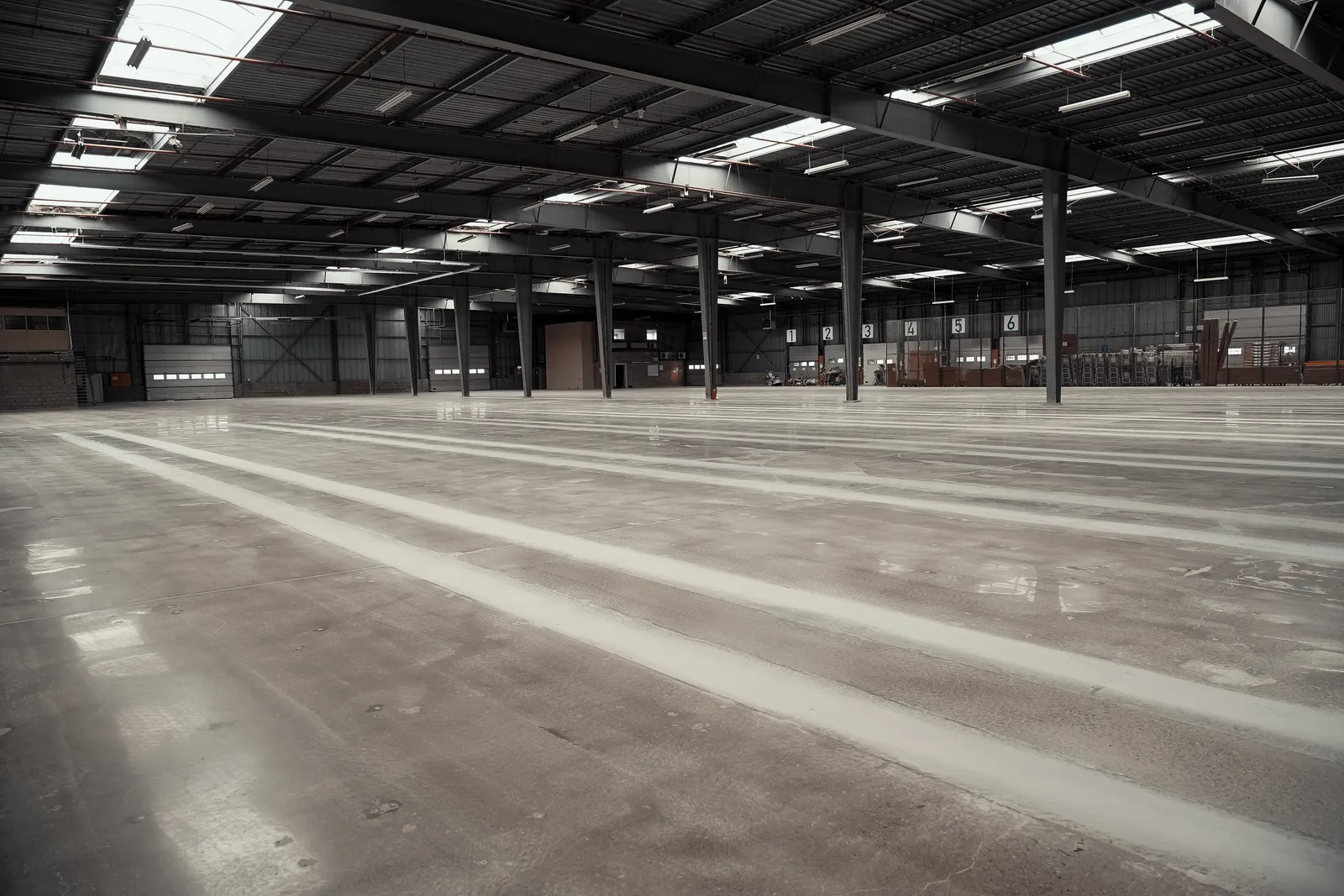 Gepolijste betonvloer in de bedrijfshal met stalen kolommen en laadpoorten