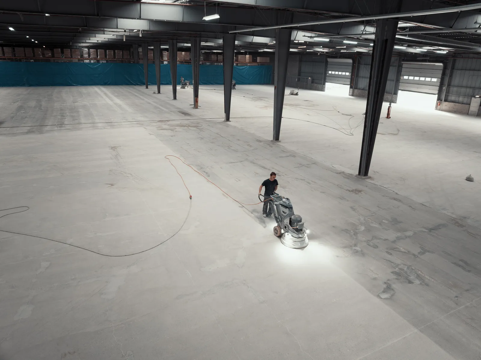 Luchtfoto van een vakman die de magazijnvloer schuurt met een diamantschuurmachine