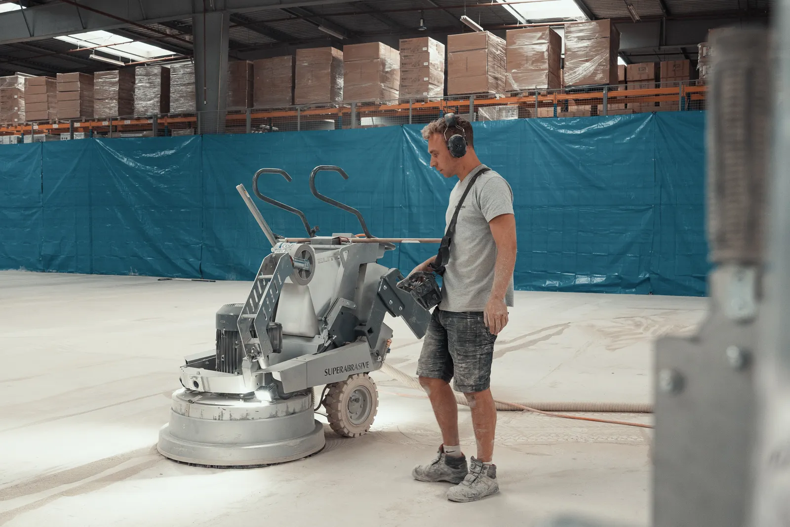 Vakman van Beton Design naast de schuurmachine in het magazijn